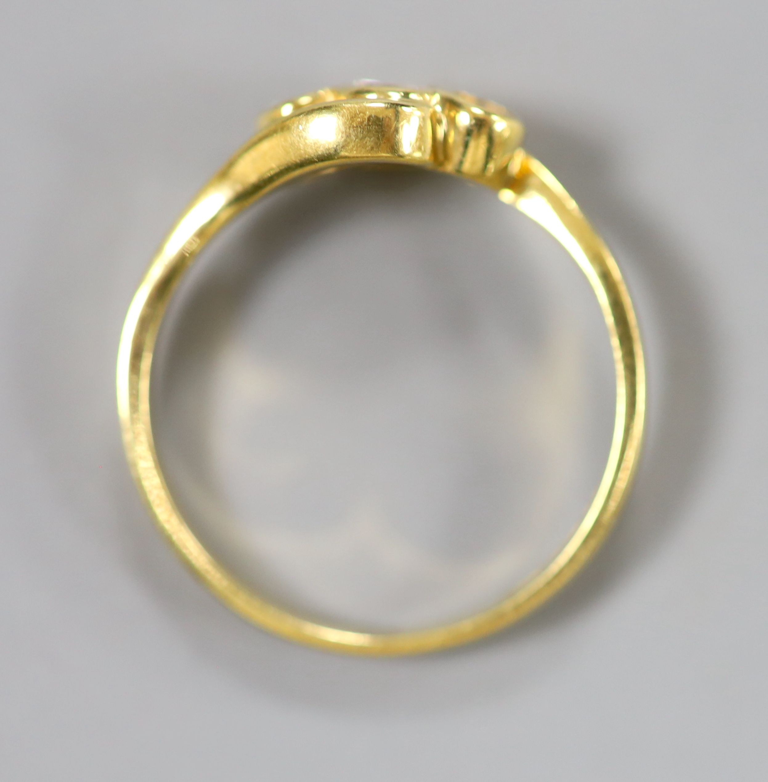 A modern 18ct gold and three stone diamond set crossover ring, size N, gross 3 grams.